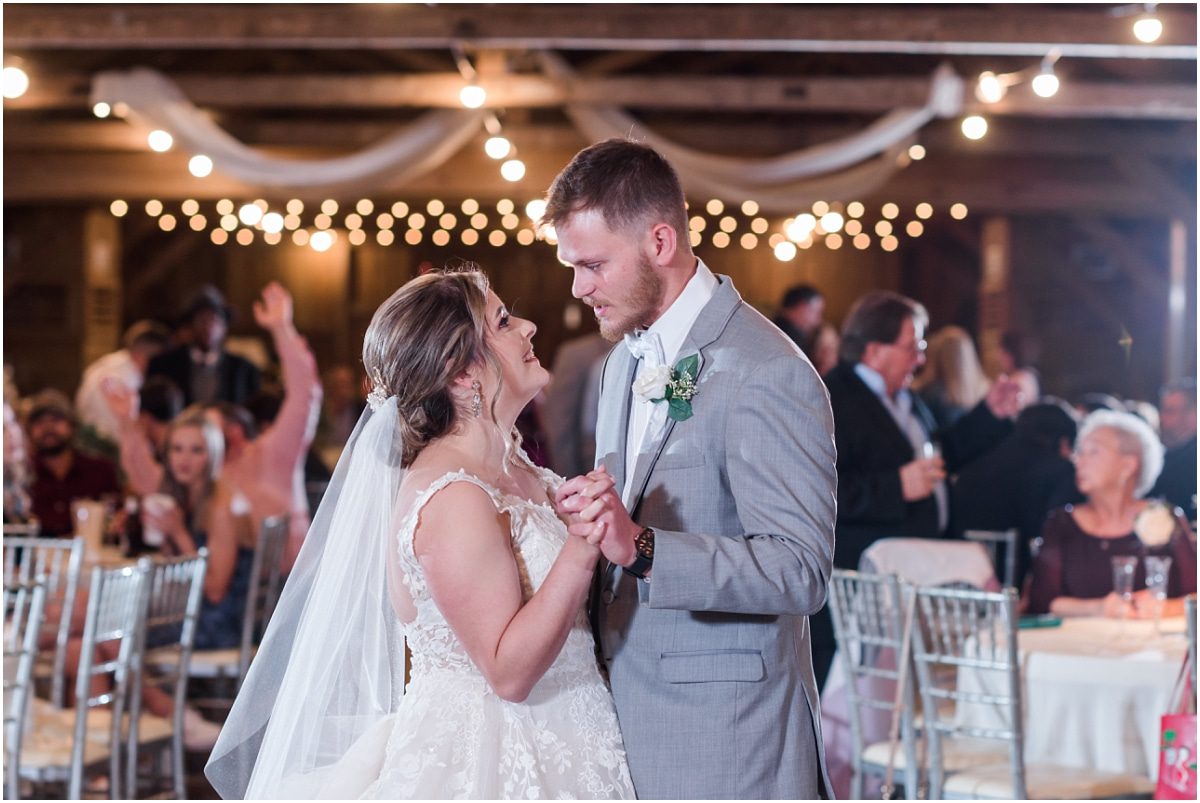 Bride and groom first dance inside rustic Mule Barn wedding venue